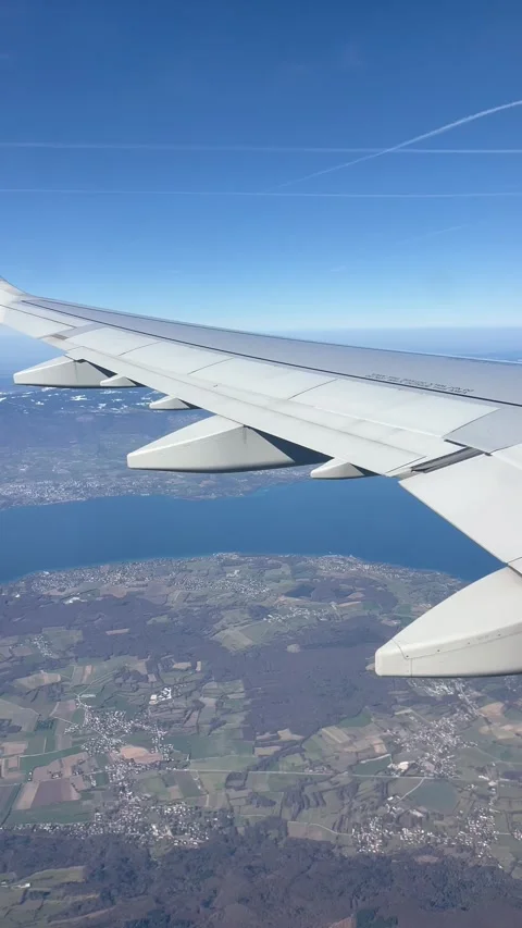 View of plane wing over land and river on a sunny day over Geneva, Switzerland Stock Footage 334429517