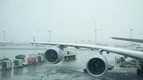 View of a plane's engines and wing on a snowy day at the airport Stock Footage 88630251