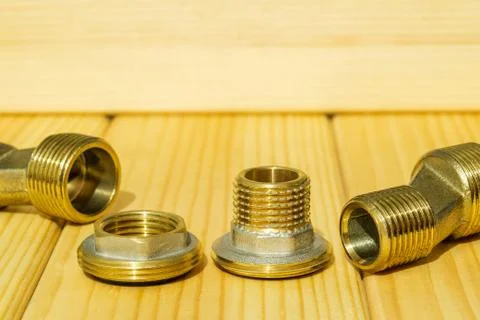 View plumbing tools brass pipe connectors on wooden board close up Stock Photos
