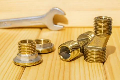 View plumbing tools brass pipe connectors on wooden board close up Stock Photos