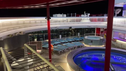 View of the pool on the upper deck of a cruise ship jacuzzi pool gym dark sky Stock Footage 295066144