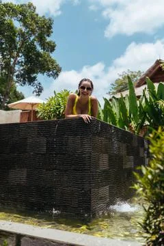 View of the pool in which stands a young girl leaning on its side surrounded by Stock Photos