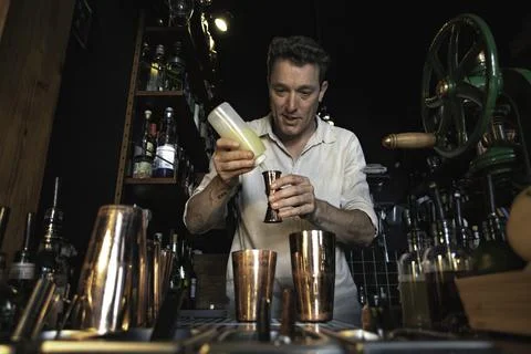 View of a professional bartender preparing a cocktail behind the counter of a Stock Photos
