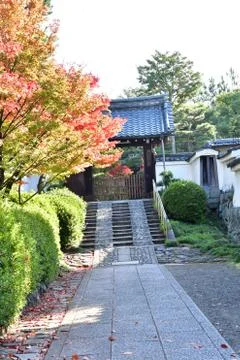 A view of a quaint old gate with a tiled roof leading to a temple. Stock Photos