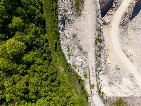 View of a quarry site next to a green forest near a dirt road with rocks an.. Stock Photos