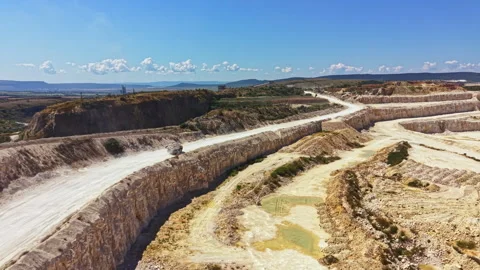 View of a quarry site with trucks and machinery operating during midday under Stock Footage 341075059
