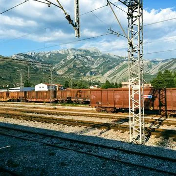 View of a rail yard with mountains in the background and overhead power lines in Stock Photos