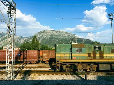 View of a rail yard with mountains in the background and overhead power lines in Stock Photos