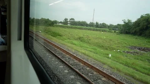 View of rails and rice fields from behind the window of a train Stock Footage 184376359