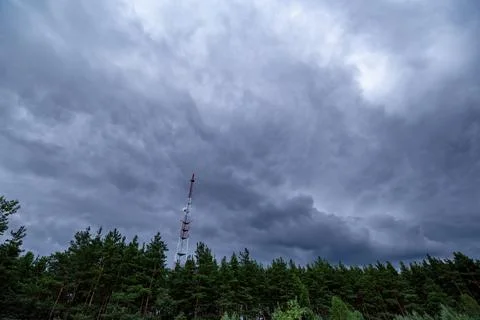 View of rain clouds with forest and mobile tower antenna in the background Stock Photos