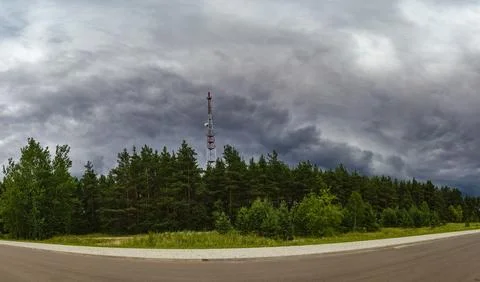 View of rain clouds with forest and mobile tower antenna in the background Stock Photos