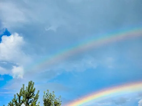 View of a rainbow in a cloudy sky. Double rainbows are a rare phenomenon. Stock Photos