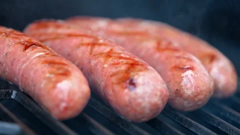 View of the raw meat sausages grilling on barbecue with open flame. Close up of Stock Footage 334021641