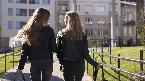 View rear of two stylish young girlfriends with long hair and stylish backpacks Stock Footage 109218083