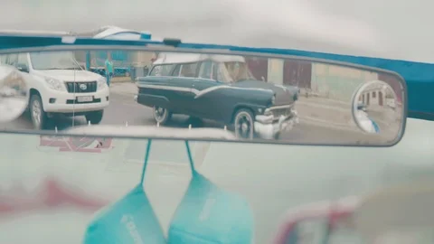 View of a rear view mirror in classic cuban car of other cars passing Stock Footage 88763420