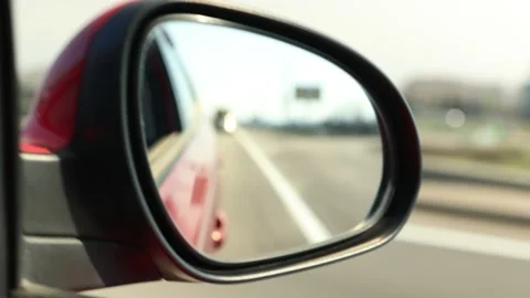 View in the rear view side mirror of a automobile, driving a red car Stock Footage 154400380
