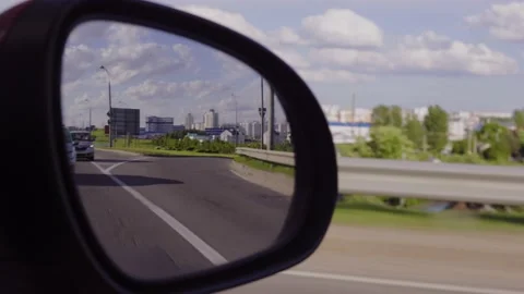 View in the rear view side mirror of a auto, driving a red car Stock Footage 165572393