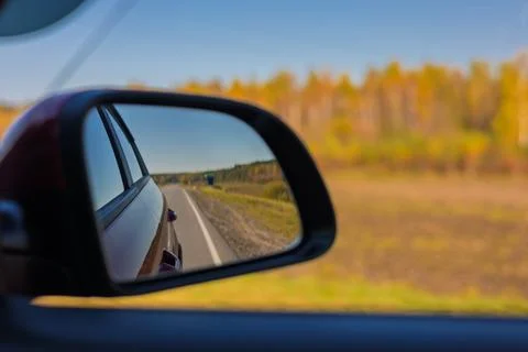 View in the rear view side mirror of a auto, driving a car along the road Stock Photos