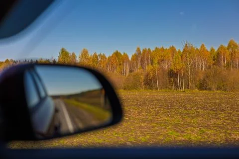 View in the rear view side mirror of a auto, driving a car along the road Stock Photos