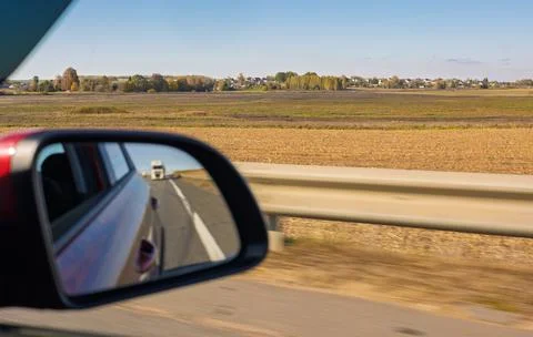 View in the rear view side mirror of a auto, driving a car along the road Stockfoto's