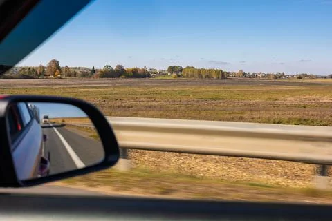 View in the rear view side mirror of a auto, driving a car along the road Stock Photos