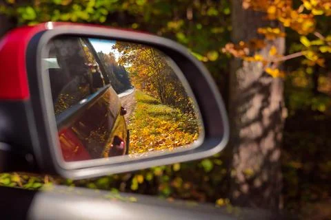 View in the rear view side mirror of a auto, driving a car along the road Stock Photos