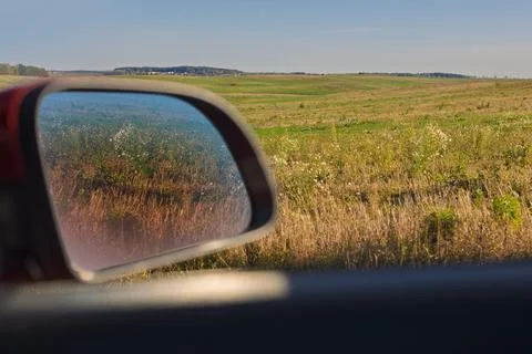 View in the rear view side mirror of a auto, driving a car along the road 库存照片