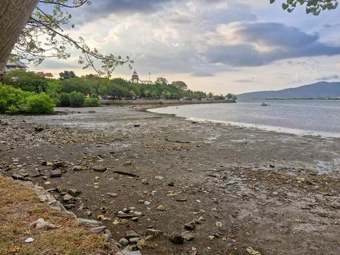 View of receding beach with cloudy sky and mountains in the background Foto stock