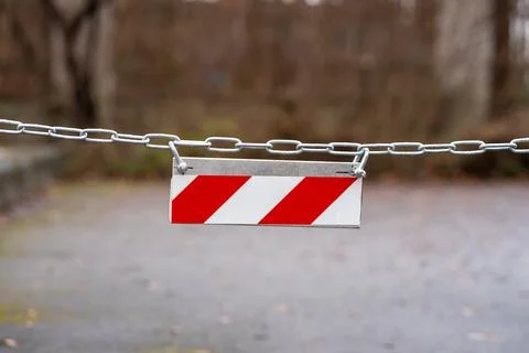 View of a red and white diagonal striped sign hanging on a chain Stock Photos