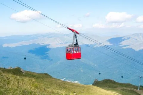 A view to red open cableway cabin over the top of the mountain and beautiful Stock Photos