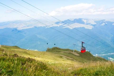 A view to red open cableway cabin over the top of the mountain and beautiful Stock Photos