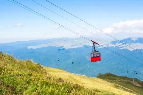 A view to red open cableway cabin over the top of the mountain and beautiful Stock Photos