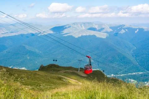 A view to red open cableway cabin over the top of the mountain and beautiful  Stock Photos
