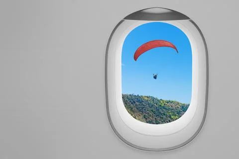 A view of a red paraglider soaring over forested mountains as seen through .. Stock Photos