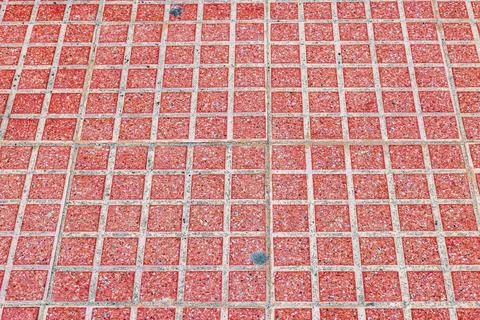 View of red square paving tiles arranged across pedestrian walkway surface. Stock Photos