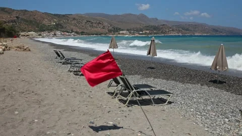 View of red warning flag on pebble beach with storm waves on Cretan Sea coast. Stock Footage 340072530