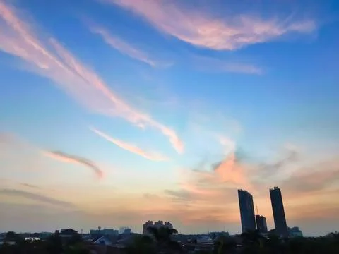 A view of reddish clouds as the sun rises over a dense urban area. Fotos Stock