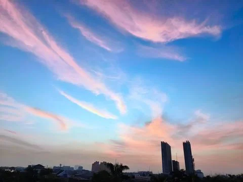 A view of reddish clouds as the sun rises over a dense urban area. Stock-Fotos
