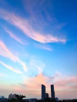 A view of reddish clouds as the sun rises over a dense urban area. Stock-Fotos
