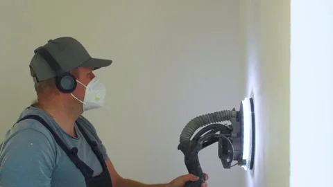 View from right of man sanding wall in house. Leveling and sanding walls after Stock-Footage 319210807
