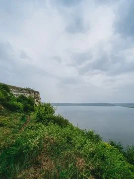 View of a river and a cloudy sky from a green hillside near a cliff in a na.. Stock Photos