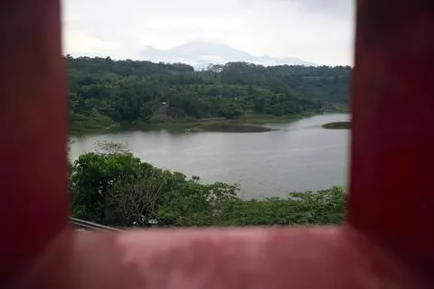 View of a river and trees seen through a red window frame Stock Photos
