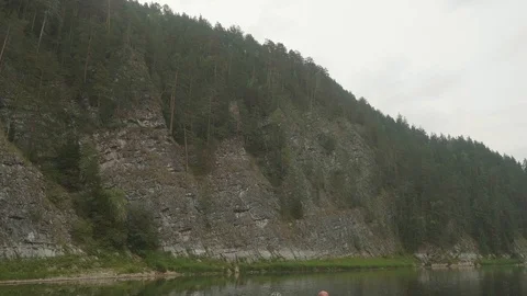 View of river bank with sheer cliffs over river. Panoramic view from floating Stock Footage 121775343