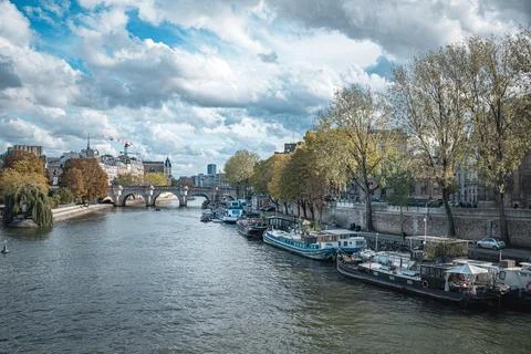 A view of a river with docked boats in front of a bridge and buildings in Paris, Fotos de archivo