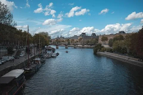 A view of a river flowing through Paris, France with several boats docked along Stock Photos