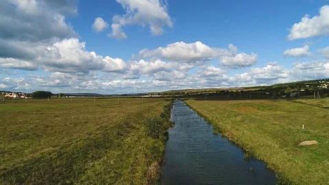A view of a river in the middle of a meadow with a beautiful background. Stock Footage 113316874