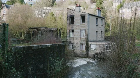 View of a river running under a partially burnt out house. 4K locked tripod Stock Footage 148148210