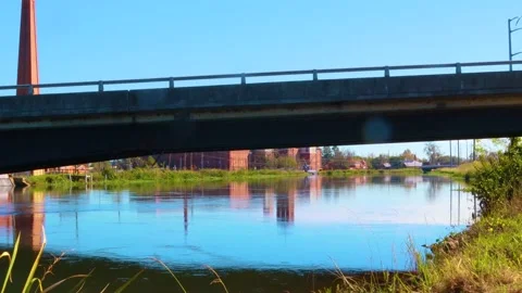 View of a river under a bridge and a factory in the background Stock Footage 143606279