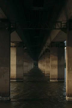 View of river under a bridge with support beams in the water. Stock Photos