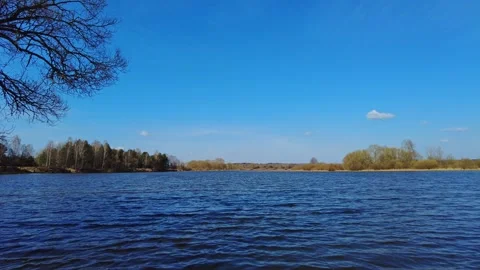 View of the river under a clear blue sky with trees along the shore in the after Stock Footage 333440654